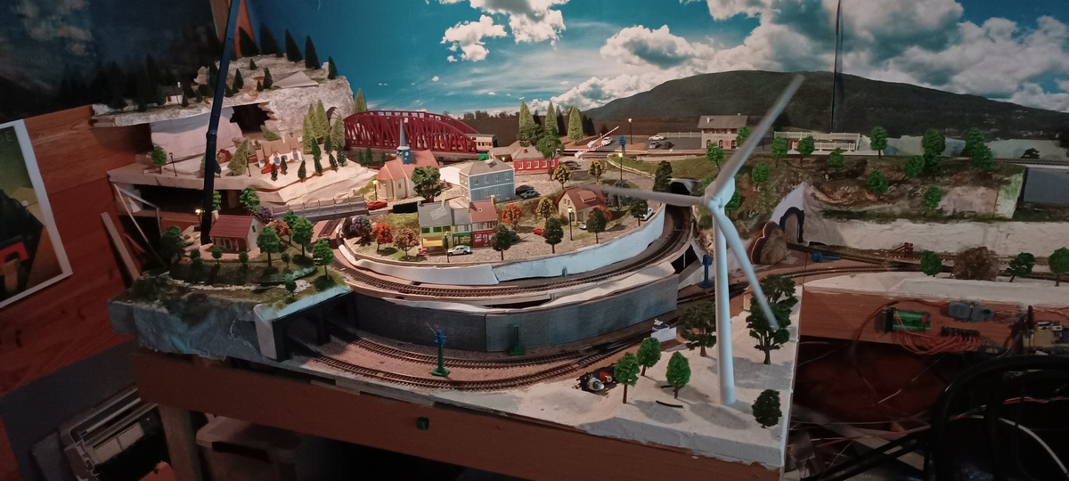 Éolienne avec village au dessus d'une double spirale ferrovoaire